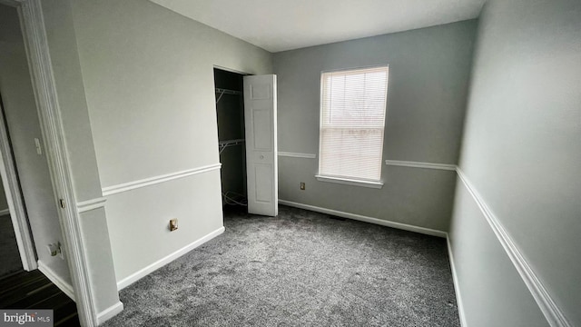 unfurnished bedroom featuring dark carpet and a closet