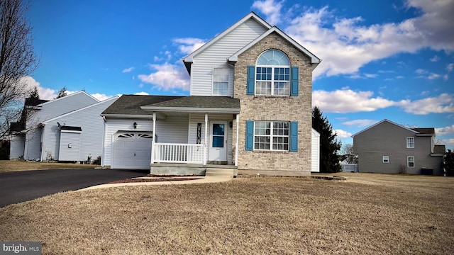 view of front property featuring a garage, covered porch, and a front yard