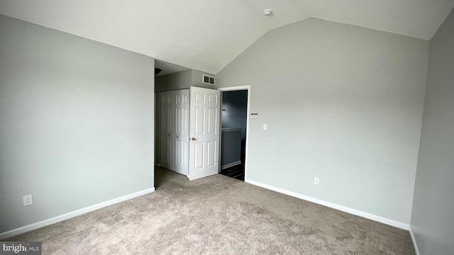 unfurnished bedroom featuring a closet, lofted ceiling, and carpet