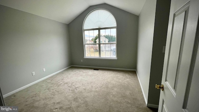 carpeted empty room featuring lofted ceiling