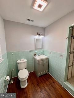 bathroom featuring wood-type flooring, toilet, tile walls, and vanity