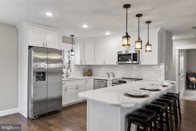 kitchen featuring stainless steel appliances, decorative light fixtures, and white cabinets