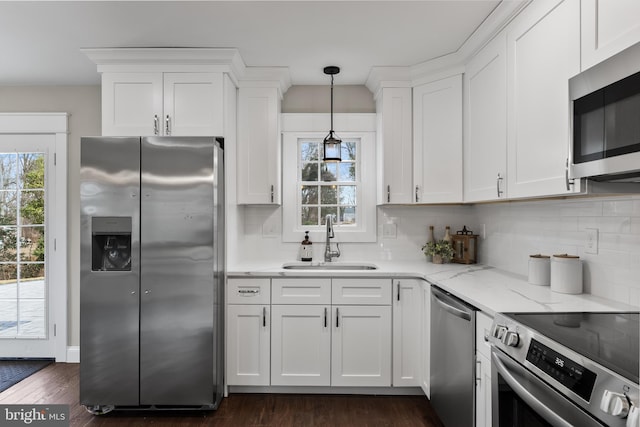 kitchen with hanging light fixtures, white cabinetry, appliances with stainless steel finishes, and sink