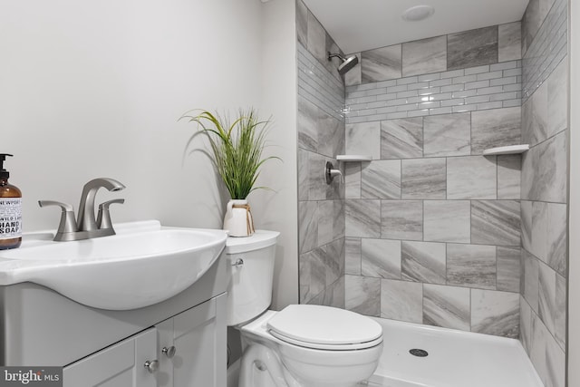 bathroom with vanity, toilet, and a tile shower