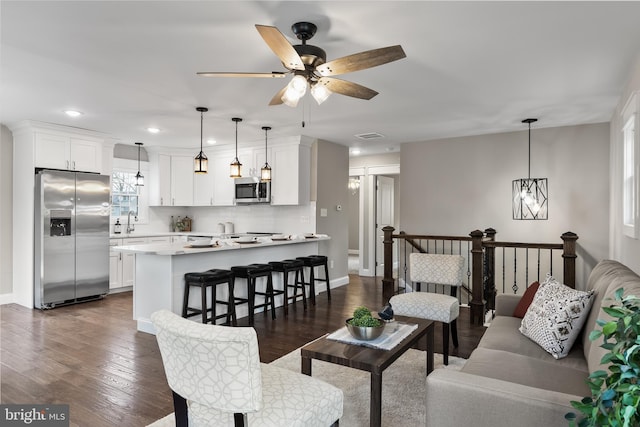 living room with dark hardwood / wood-style flooring, sink, and ceiling fan with notable chandelier