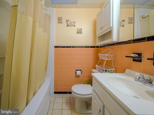 full bathroom with tile walls, vanity, toilet, tile patterned floors, and shower / bath combo with shower curtain