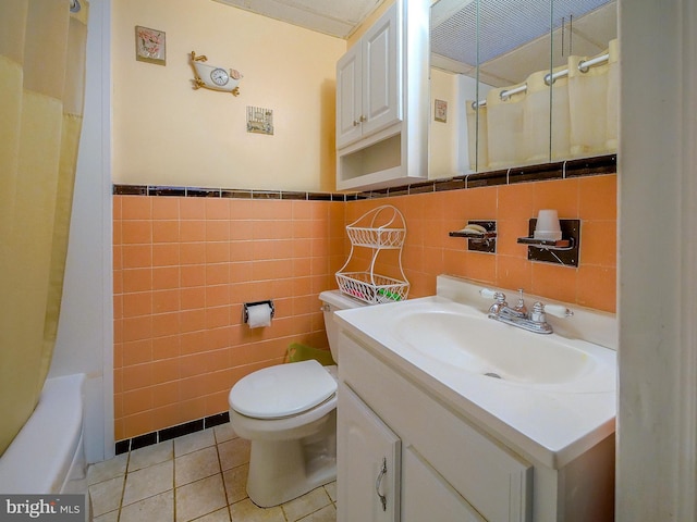 full bathroom with tile patterned flooring, shower / tub combo, tile walls, vanity, and toilet