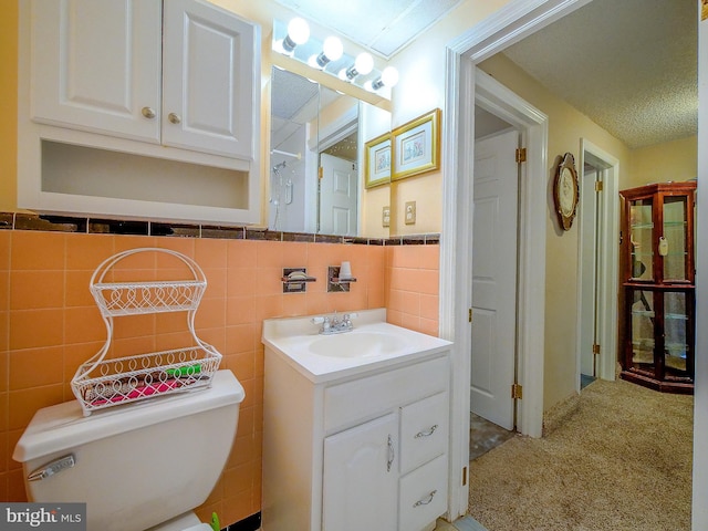 bathroom with vanity, tile walls, a textured ceiling, and toilet