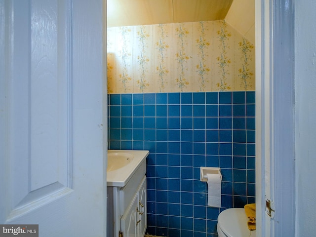 bathroom with vanity, toilet, and tile walls