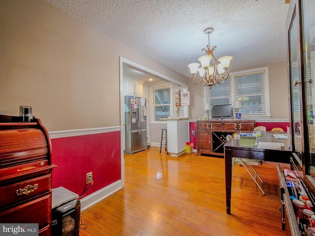 dining room featuring an inviting chandelier, light hardwood / wood-style flooring, and a textured ceiling