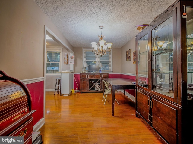 dining room featuring a chandelier, a textured ceiling, and light hardwood / wood-style floors