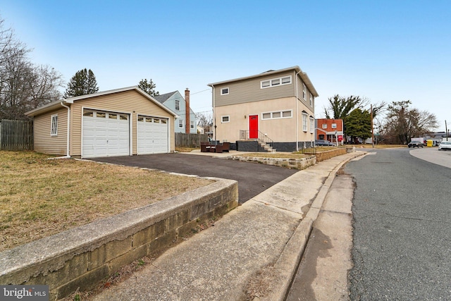 view of front of house with a garage, an outdoor structure, fence, and entry steps