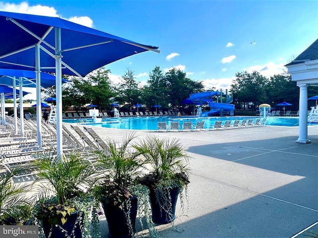 view of swimming pool with a water slide and a patio