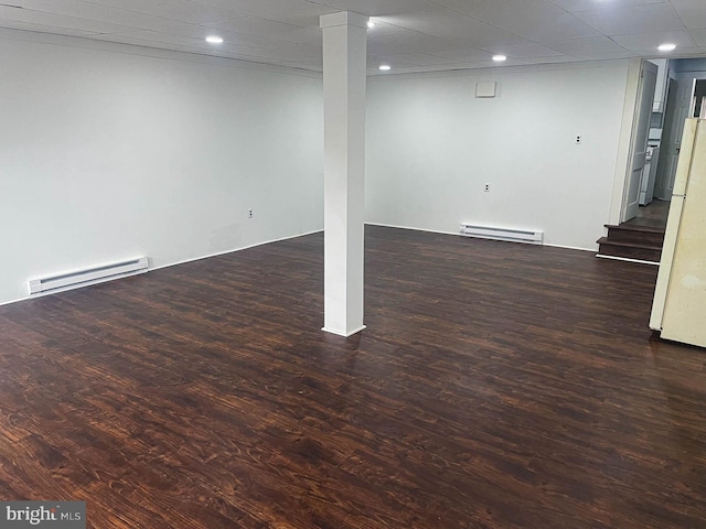 basement featuring white refrigerator, a baseboard radiator, and dark hardwood / wood-style flooring