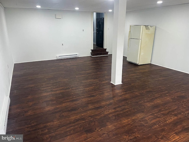 basement featuring dark hardwood / wood-style flooring, a baseboard radiator, and white refrigerator