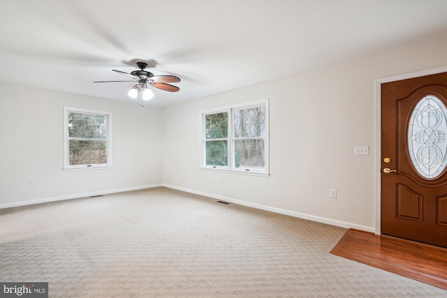 foyer entrance featuring a wealth of natural light, ceiling fan, and carpet