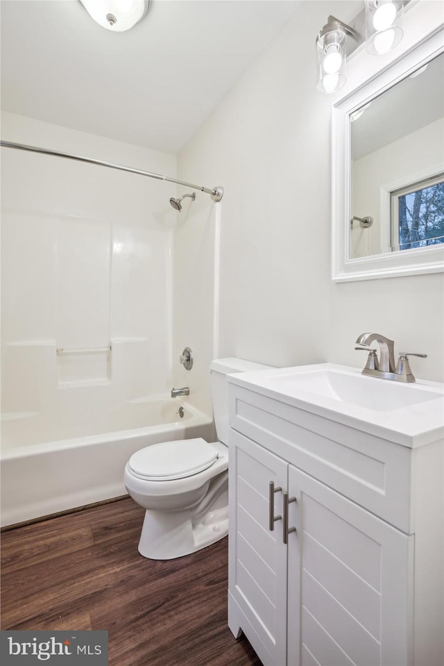 full bathroom featuring hardwood / wood-style flooring, vanity, washtub / shower combination, and toilet