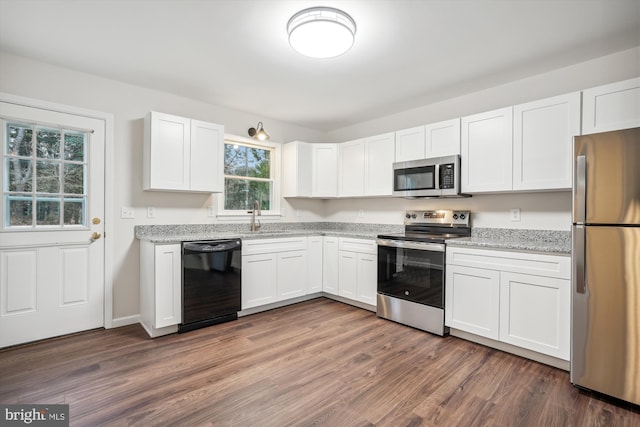 kitchen with appliances with stainless steel finishes, sink, white cabinets, and dark hardwood / wood-style floors