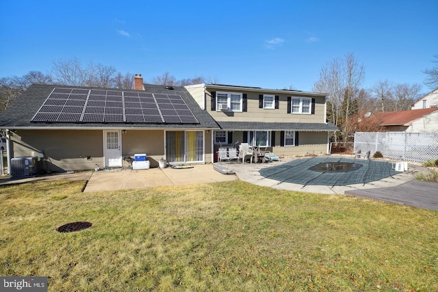 rear view of house with a yard, a patio area, central air condition unit, and solar panels