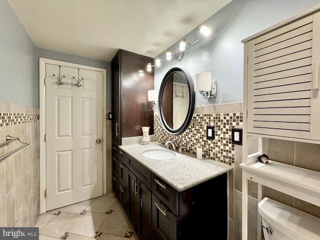 bathroom featuring vanity, toilet, and tile walls