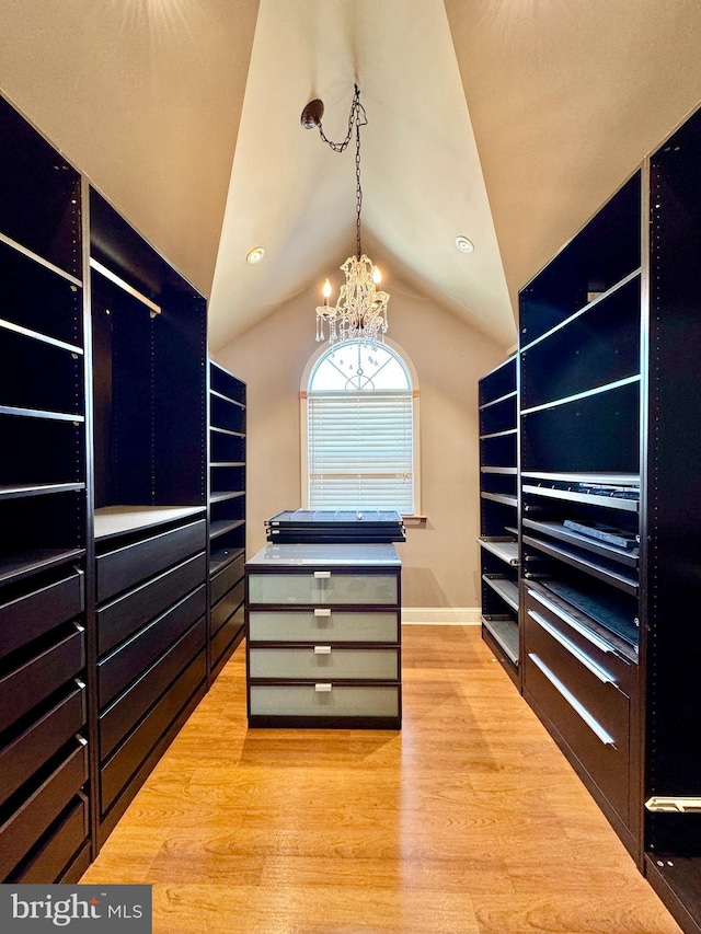 spacious closet featuring vaulted ceiling, an inviting chandelier, and light wood-type flooring