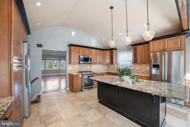 kitchen with appliances with stainless steel finishes, a kitchen island, light stone counters, a kitchen bar, and decorative light fixtures