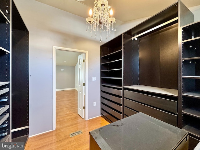 walk in closet featuring an inviting chandelier and wood-type flooring