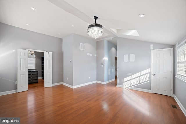 unfurnished living room featuring lofted ceiling, hardwood / wood-style floors, and an inviting chandelier