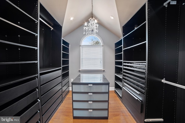 spacious closet with vaulted ceiling, a notable chandelier, and light hardwood / wood-style flooring