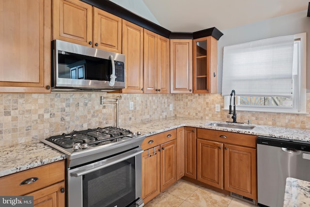 kitchen featuring tasteful backsplash, sink, stainless steel appliances, and light stone countertops