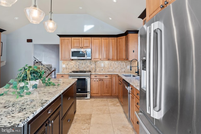 kitchen with vaulted ceiling, appliances with stainless steel finishes, sink, hanging light fixtures, and light stone countertops