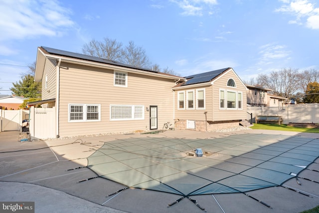 rear view of house with a covered pool, a patio area, and solar panels