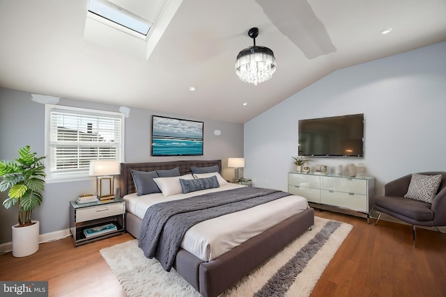 bedroom featuring wood-type flooring, lofted ceiling with skylight, and a chandelier