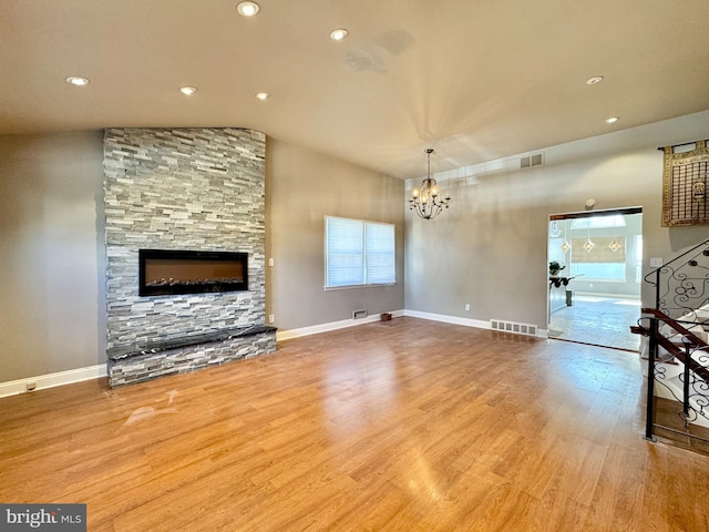 unfurnished living room with a notable chandelier, vaulted ceiling, and light hardwood / wood-style floors