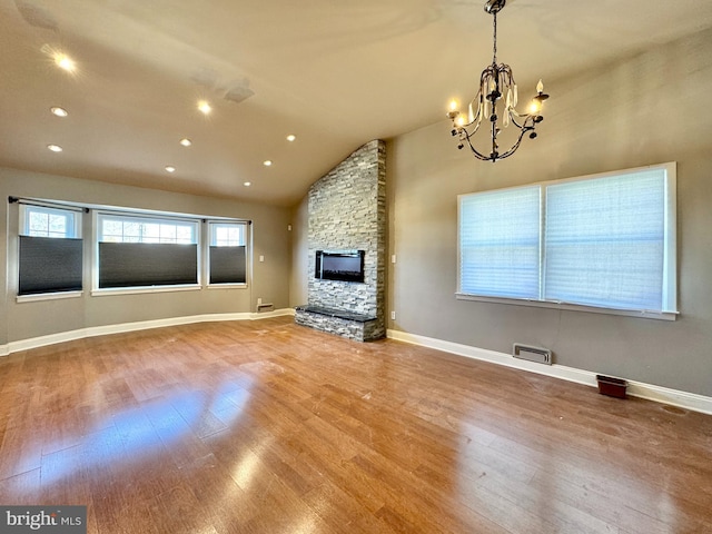 unfurnished living room featuring lofted ceiling, hardwood / wood-style flooring, a fireplace, and a chandelier