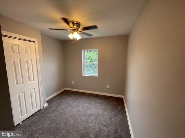 spare room featuring dark carpet and ceiling fan