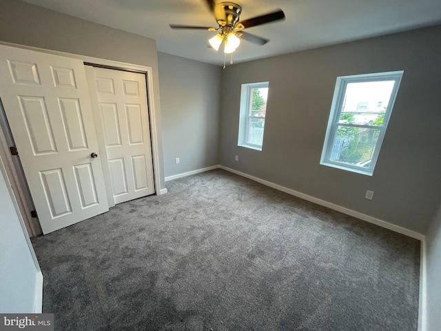 unfurnished bedroom featuring dark carpet, a closet, and ceiling fan