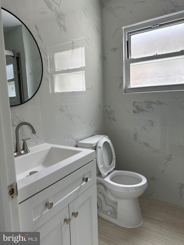 bathroom with vanity, toilet, and tile walls