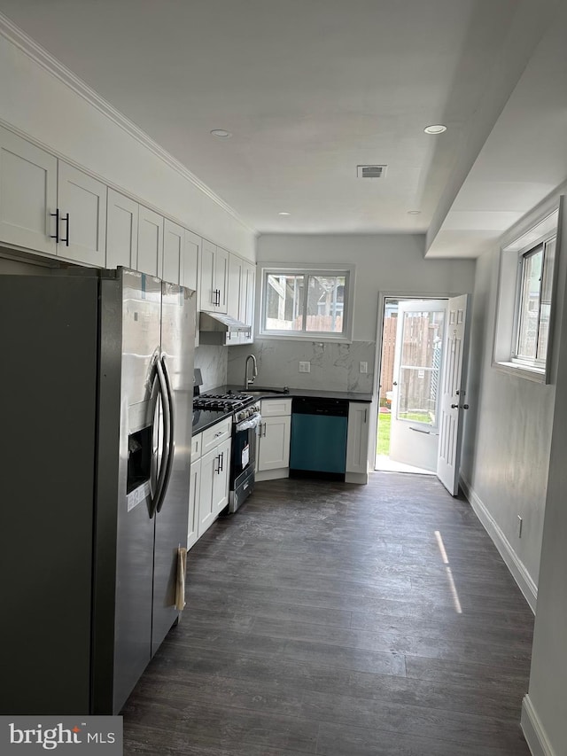 kitchen featuring dark hardwood / wood-style floors, tasteful backsplash, white cabinetry, sink, and stainless steel appliances