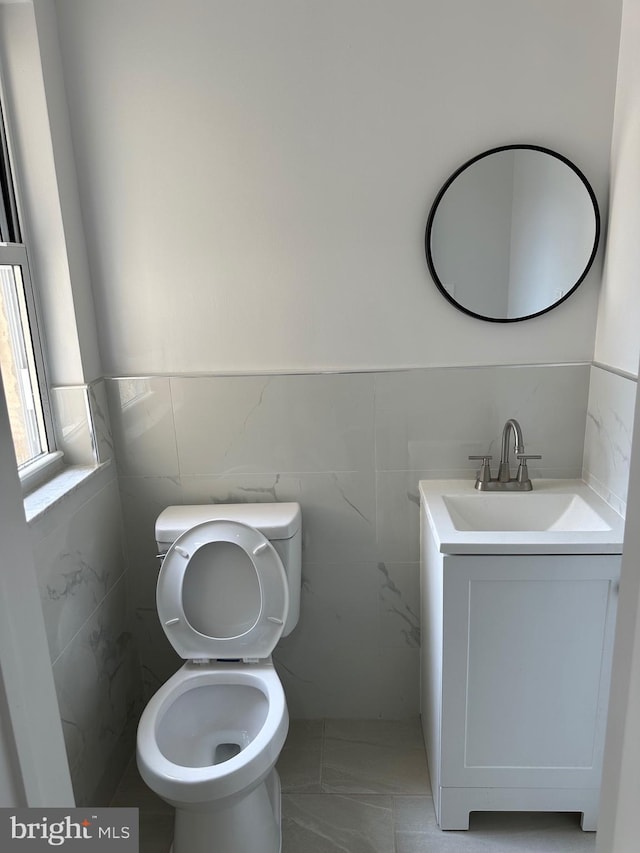 bathroom with vanity, toilet, and tile walls