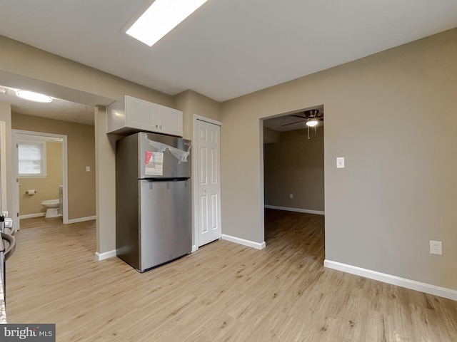 kitchen featuring ceiling fan, light hardwood / wood-style floors, stainless steel refrigerator, and white cabinets