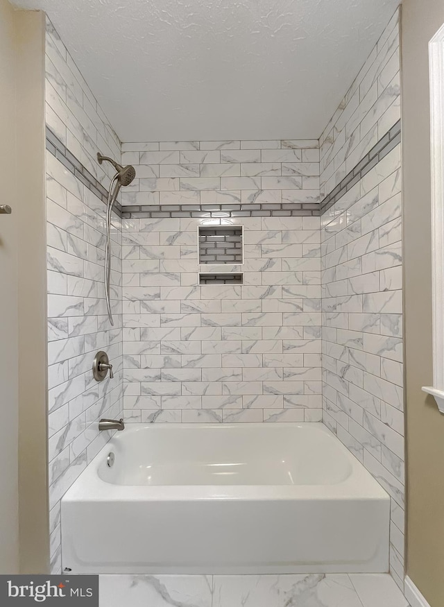 bathroom featuring tiled shower / bath combo and a textured ceiling