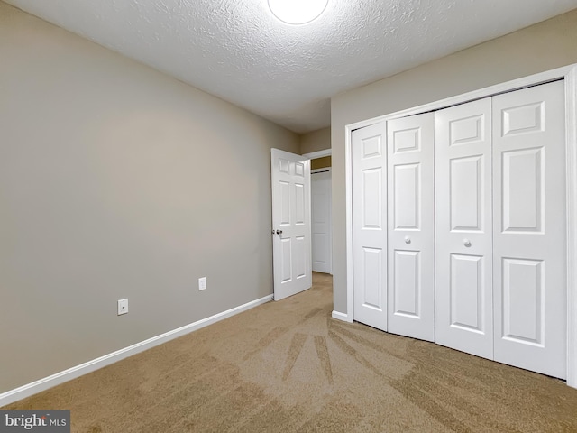 unfurnished bedroom featuring carpet floors, a textured ceiling, and a closet