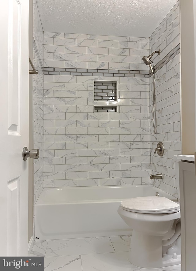 full bathroom with tiled shower / bath, vanity, a textured ceiling, and toilet