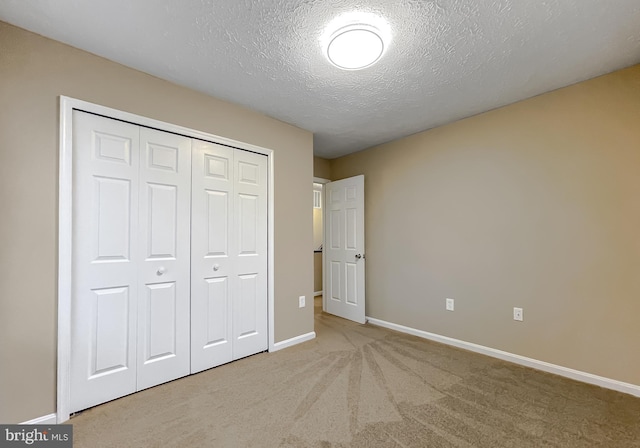 unfurnished bedroom featuring light carpet, a textured ceiling, and a closet