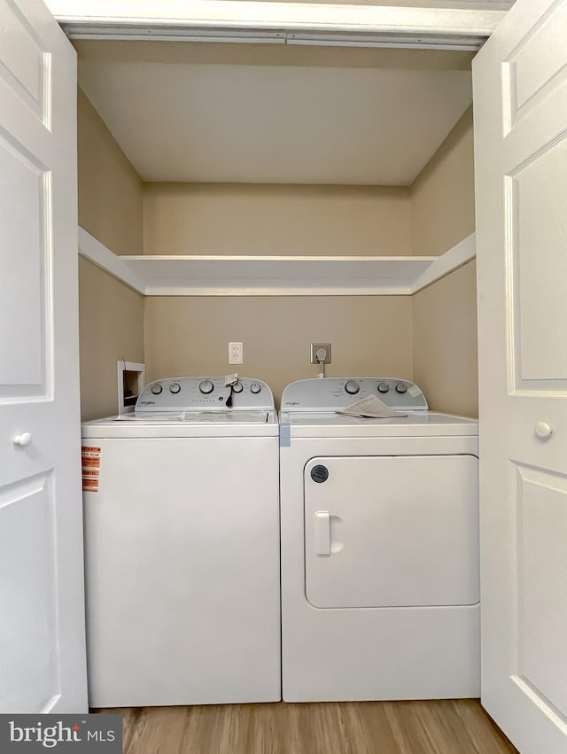 clothes washing area with independent washer and dryer and light wood-type flooring