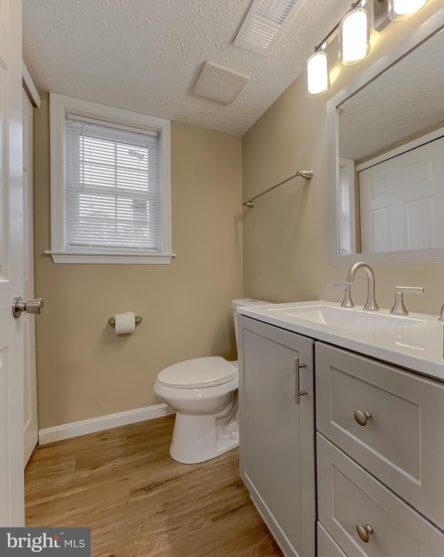 bathroom with vanity, hardwood / wood-style floors, a textured ceiling, and toilet