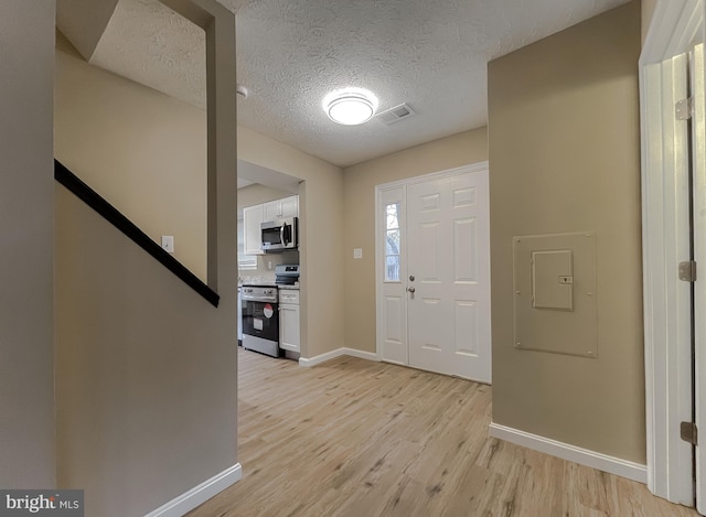 entrance foyer with light hardwood / wood-style flooring and a textured ceiling