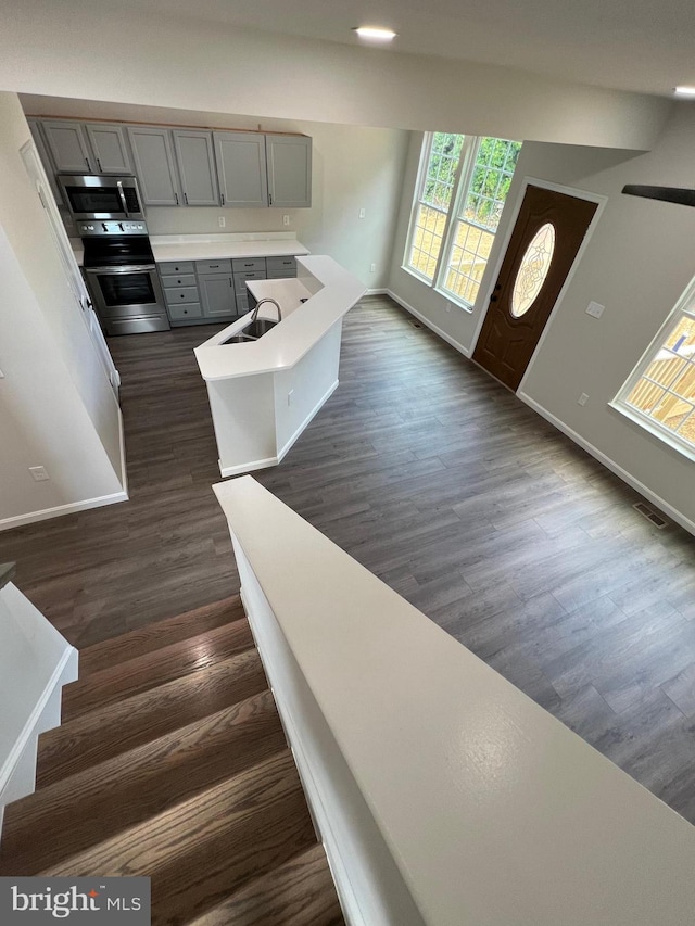 interior space featuring stainless steel appliances, gray cabinets, and dark wood-type flooring