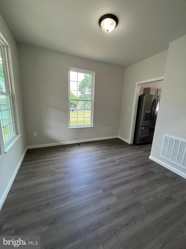 spare room with baseboards, visible vents, and dark wood-type flooring